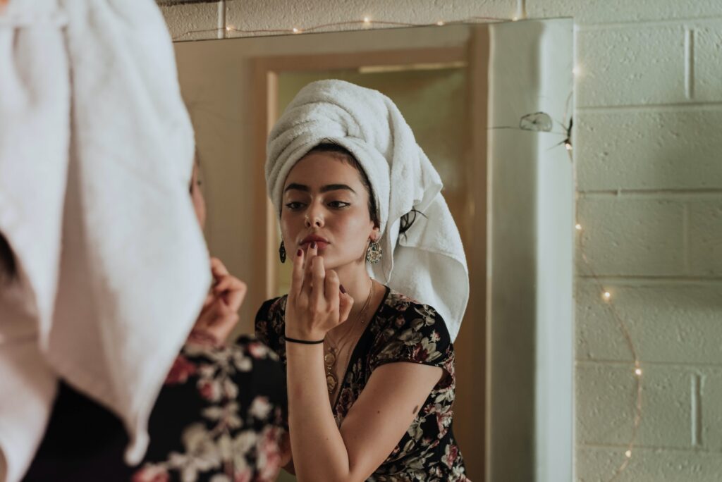 mujer pintandose los labios frente a un espejo