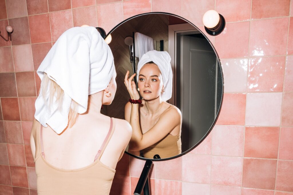mujer mirandose en el espejo con un toallon en el pelo